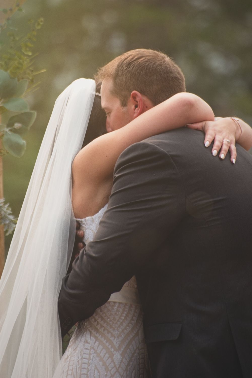 The bride and groom embrace under the altar while exchanging vows.