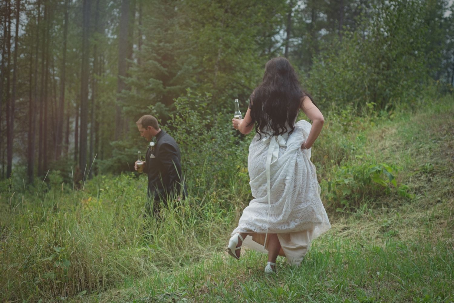 Bride and groom sneak away to share a drink in the forest after their ceremony.