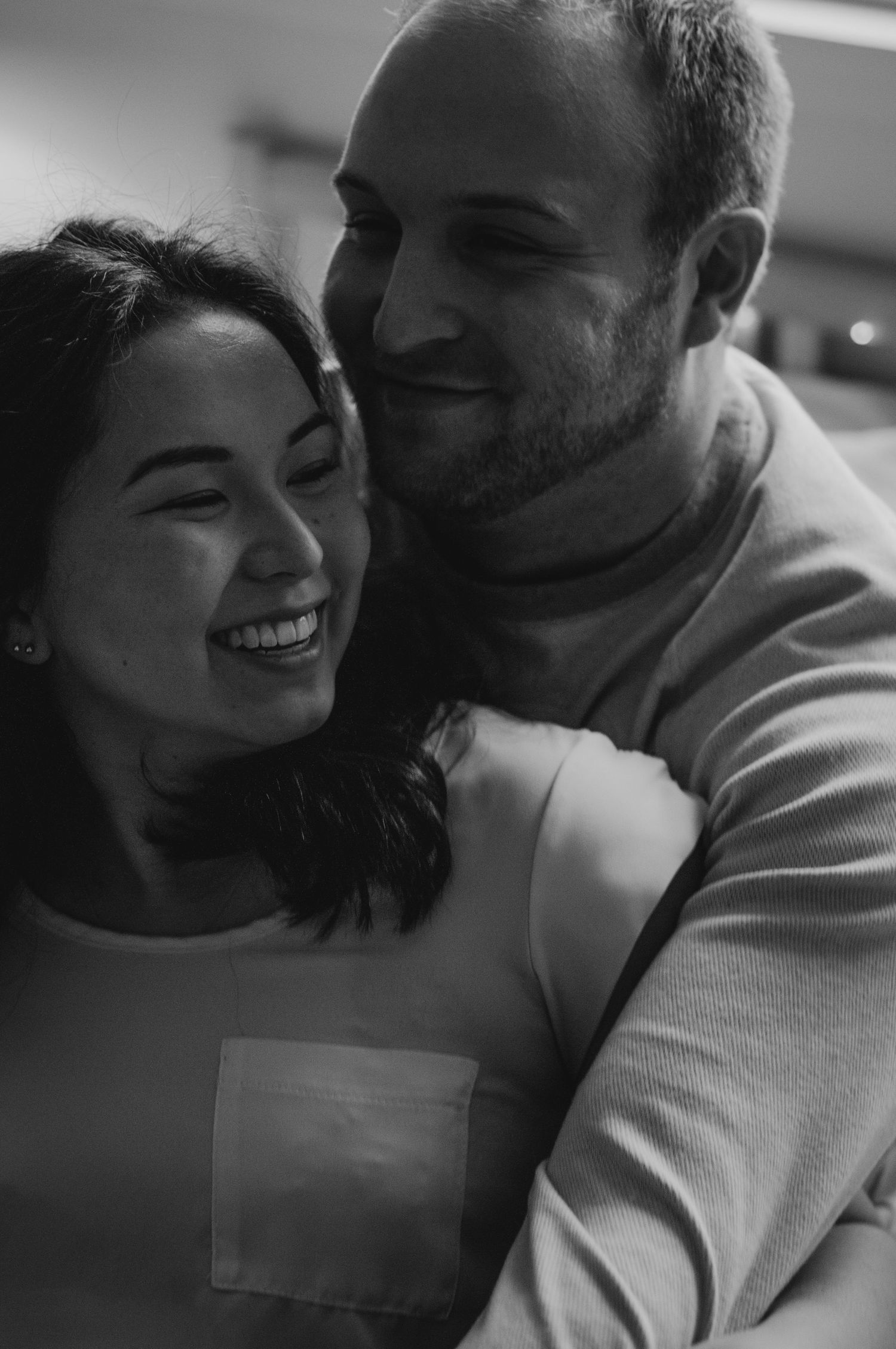 Couple smiles together while snuggling.