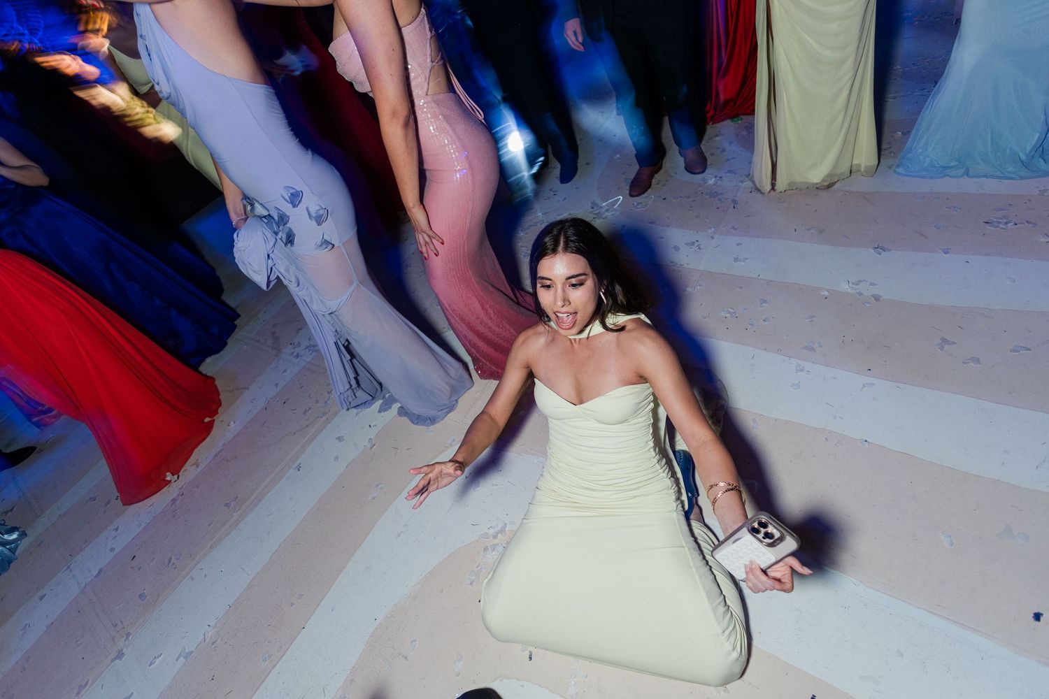 Woman in white dress sitting on floor at formal event.