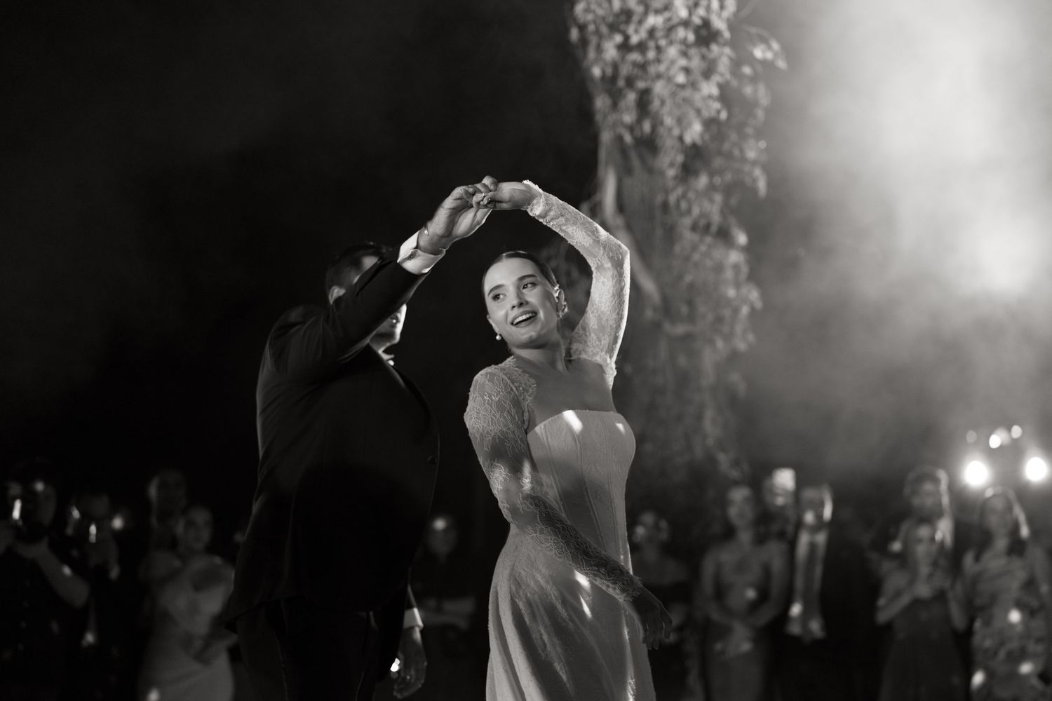 Bride and groom share elegant first dance in black and white wedding photo with dramatic smoke effects.