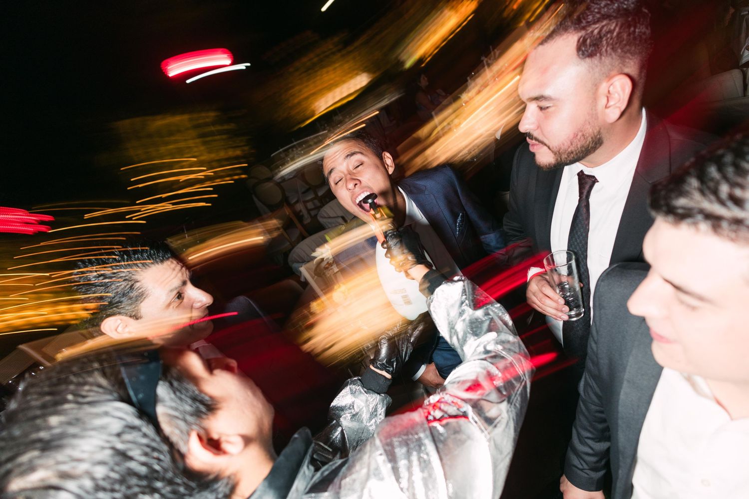 Men celebrating at nighttime event with motion blur effect.