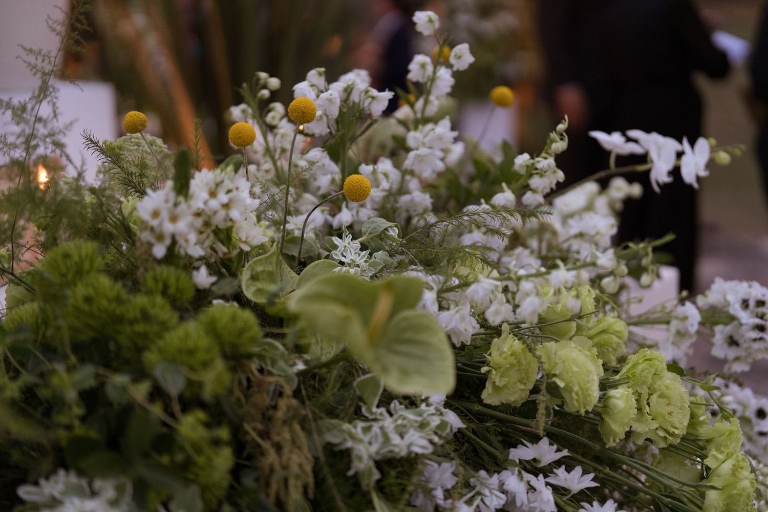 Lush wedding floral arrangement featuring white orchids, chamomile, and green blooms as centerpiece.
