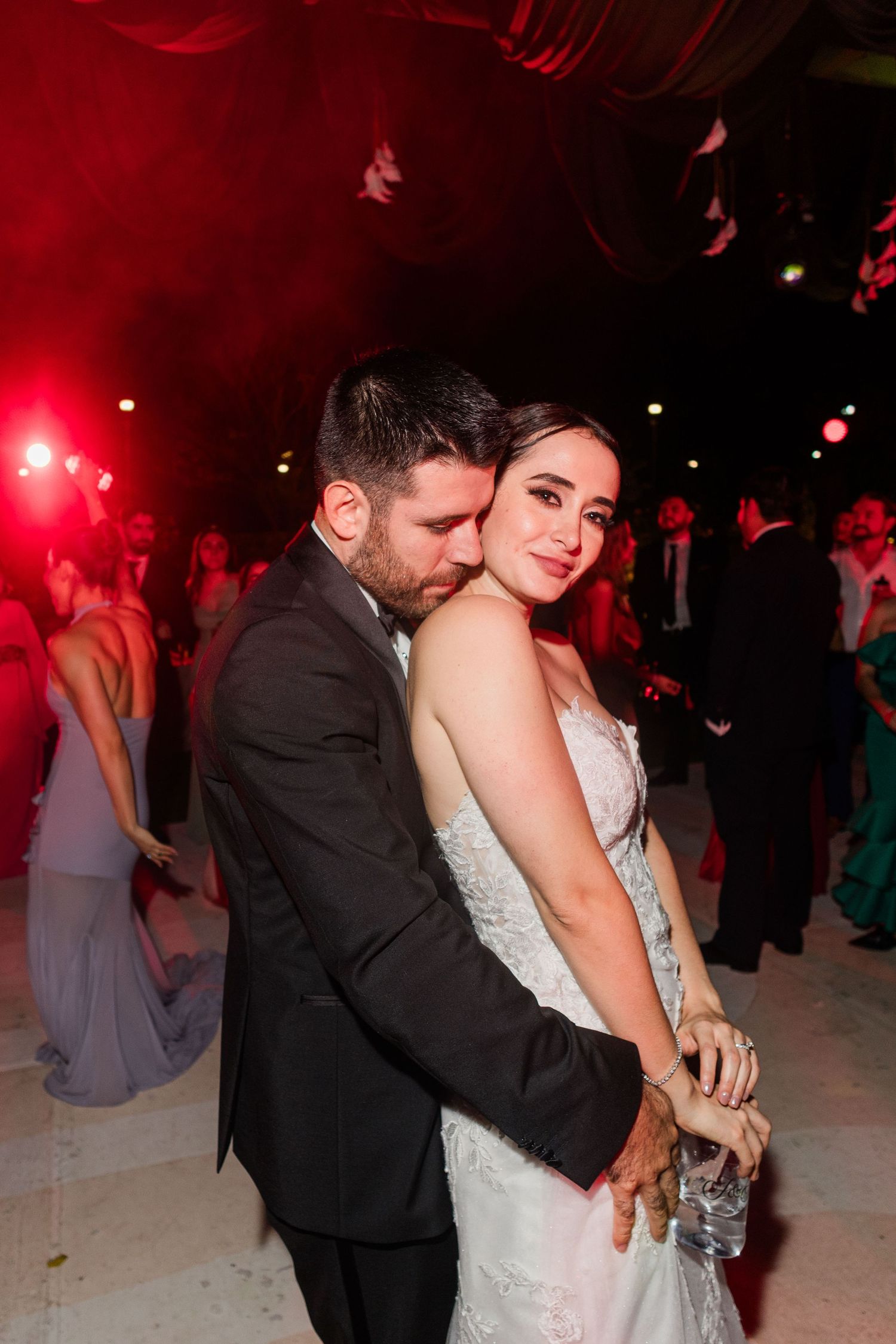 Bride and groom embracing tenderly on wedding reception dance floor.
