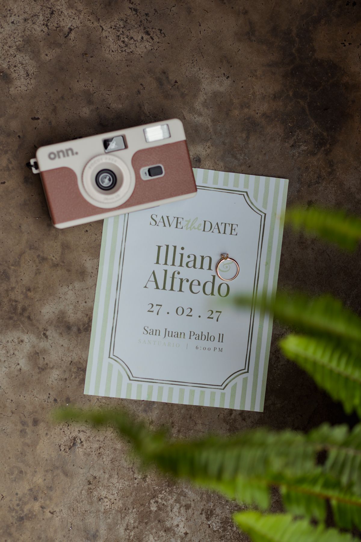 Save the date card for Illiano and Alfredo on February 27 with engagement ring and vintage camera.