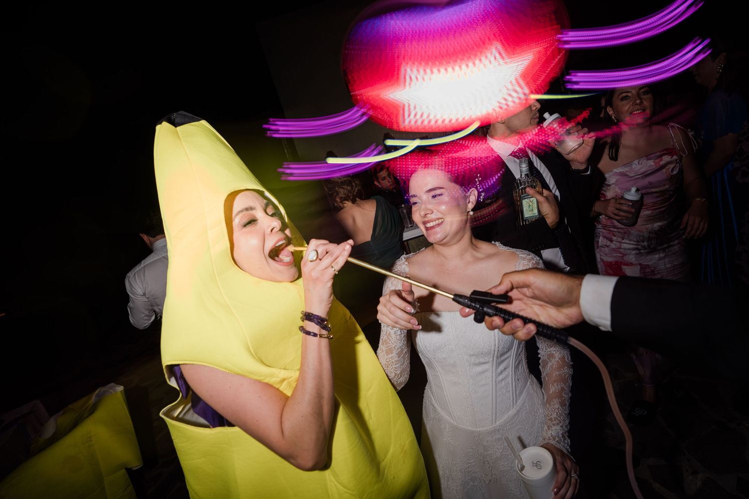 Guest in banana costume and bride enjoying sparklers at a fun wedding celebration.