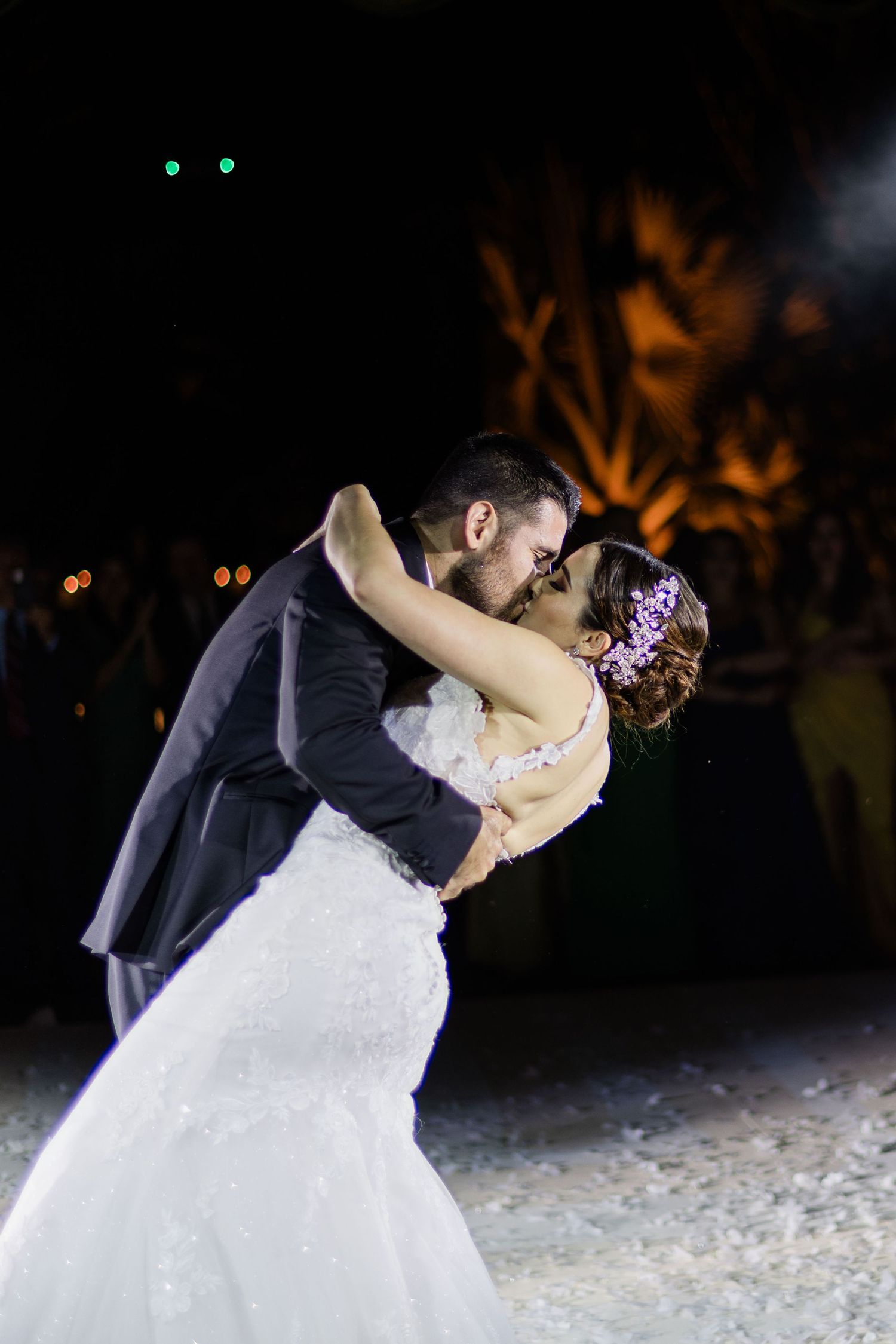 Bride and groom sharing romantic kiss on outdoor dance floor.