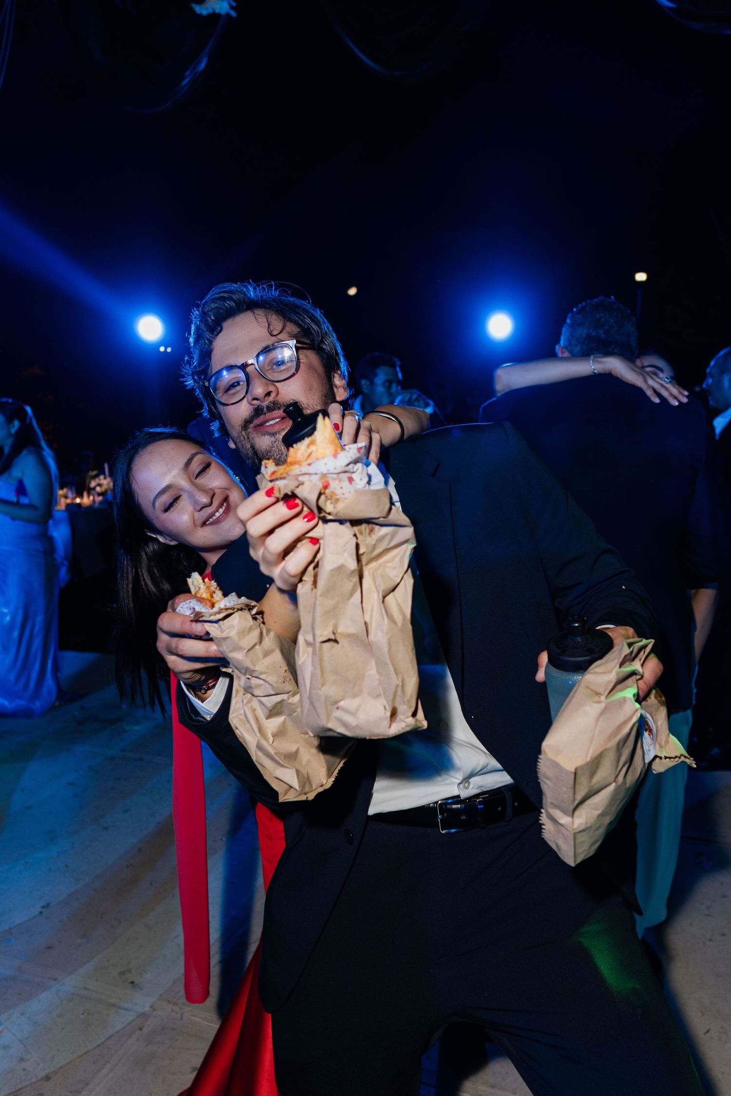 Couple sharing food happily at wedding reception dance floor.