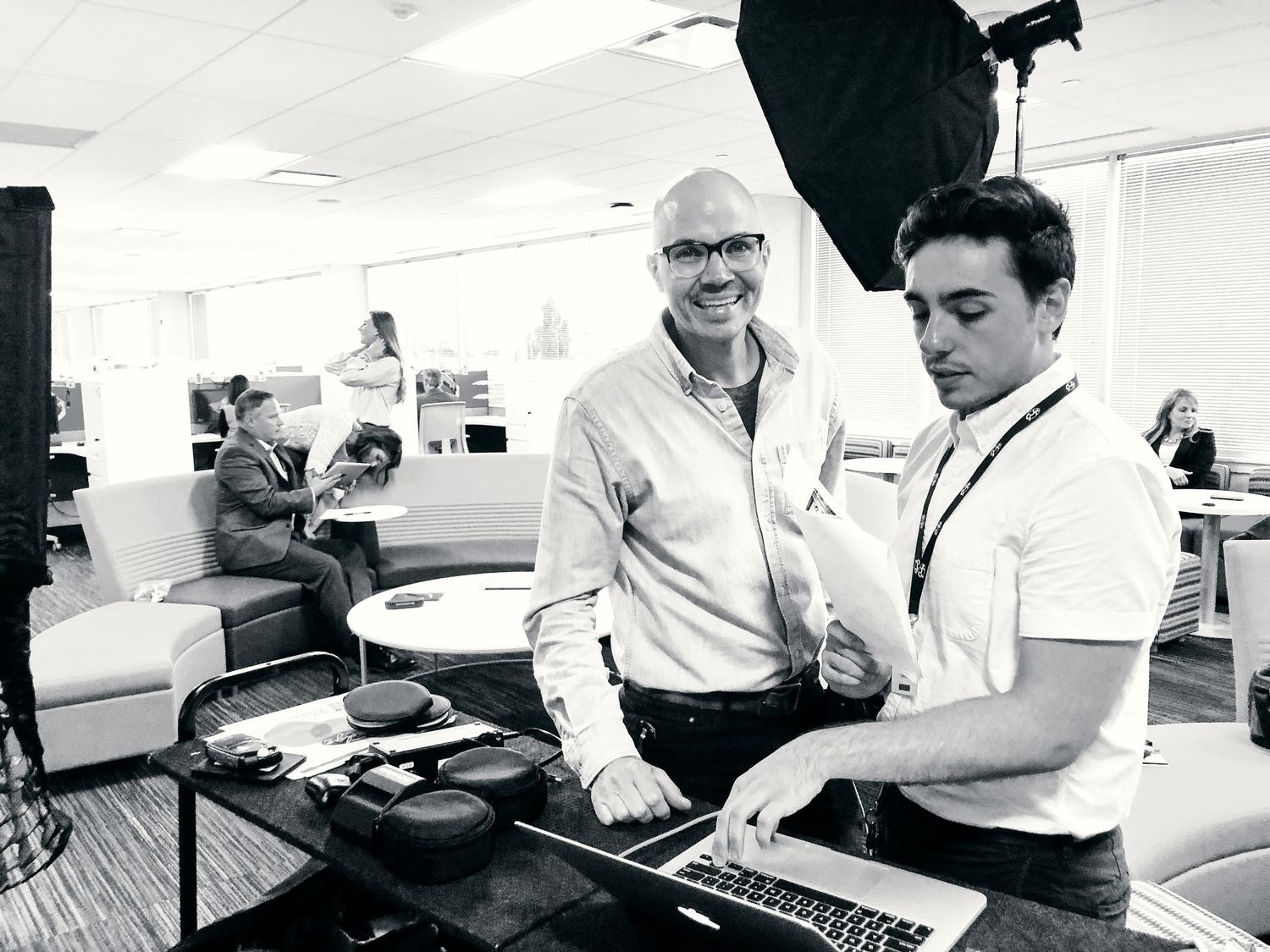 Two professionals collaborating over a laptop in a modern office during a video production setup.