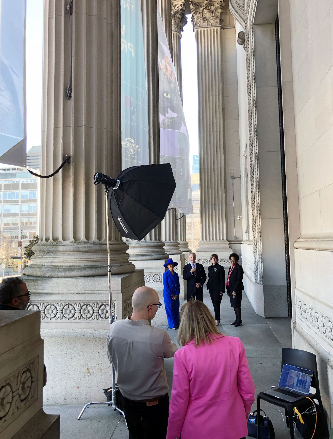 Behind-the-scenes photo shoot setup outside a classical architecture building.