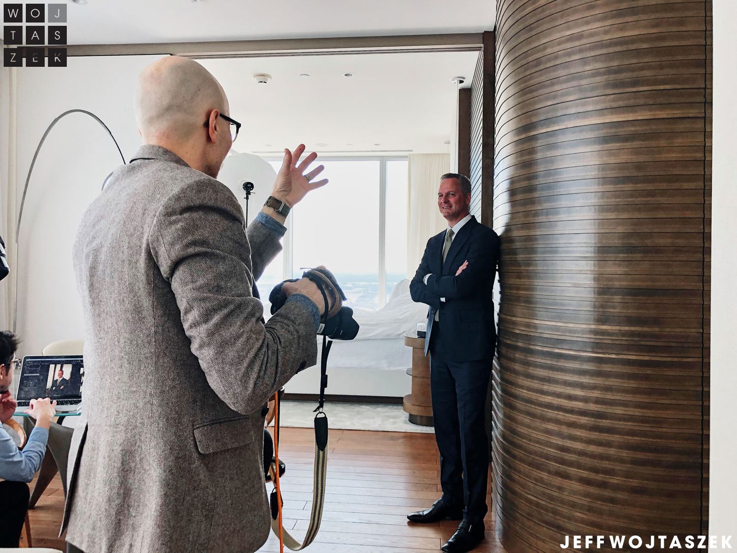 Photographer directing a man in a suit during an indoor photo shoot with professional lighting equipment.