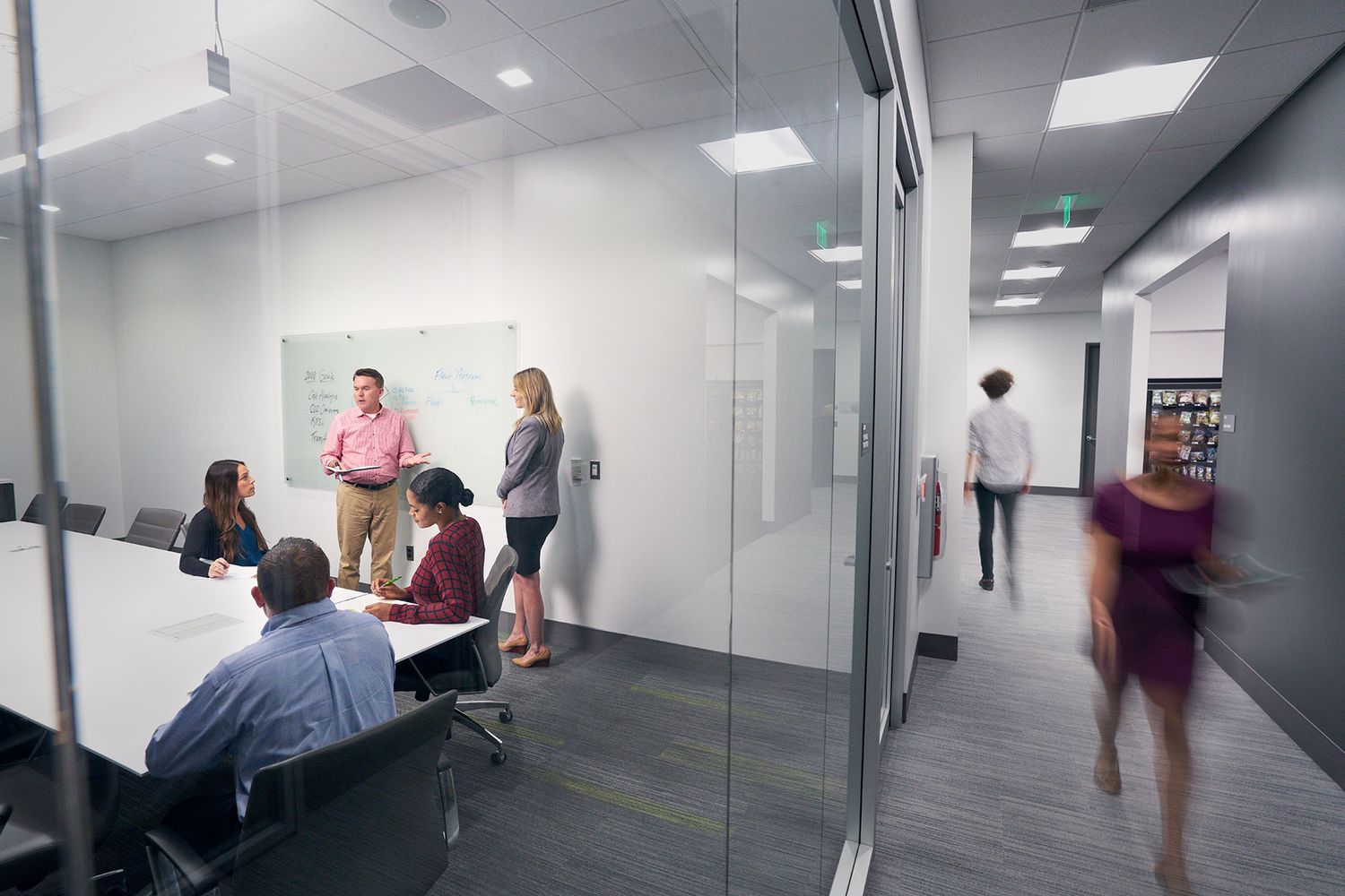 Team meeting in a modern glass-walled conference room with employees collaborating.