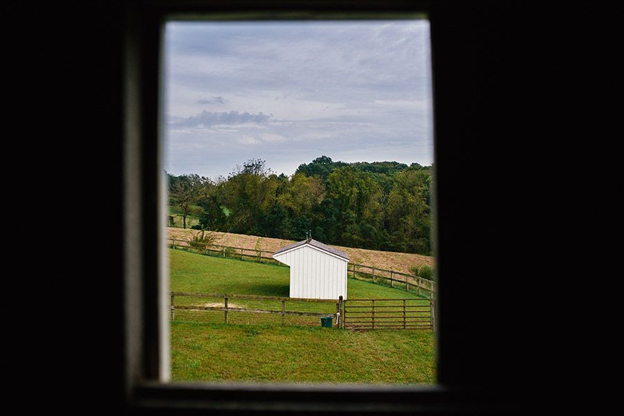 Scenic rural farmland with a white barn viewed through a dark window frame.