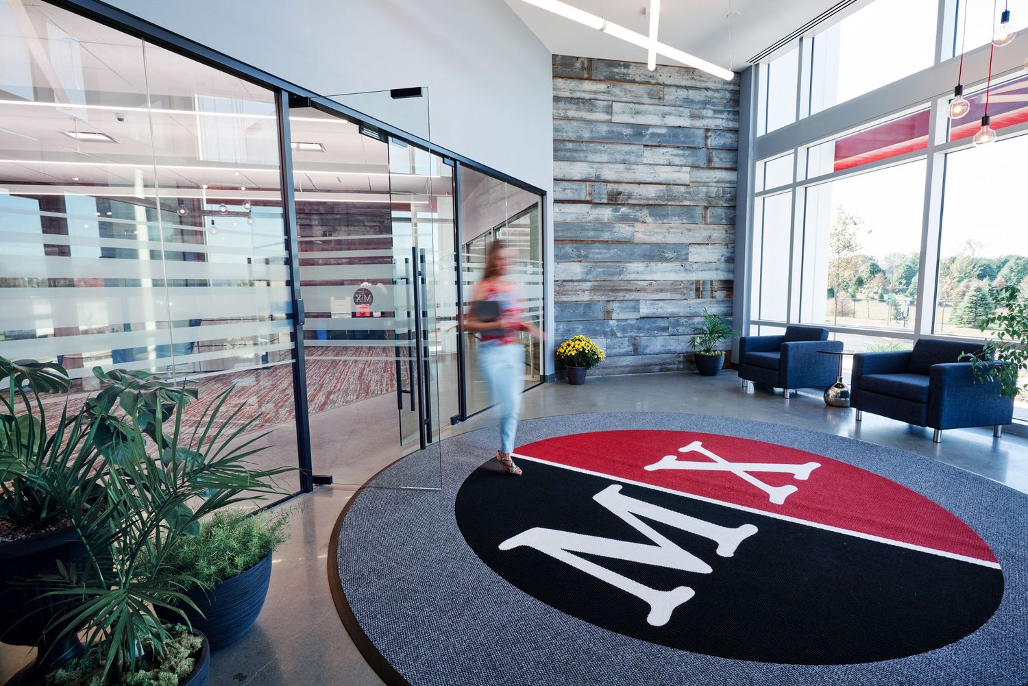 Modern office lobby with MA logo floor mat, glass doors, and contemporary seating area.