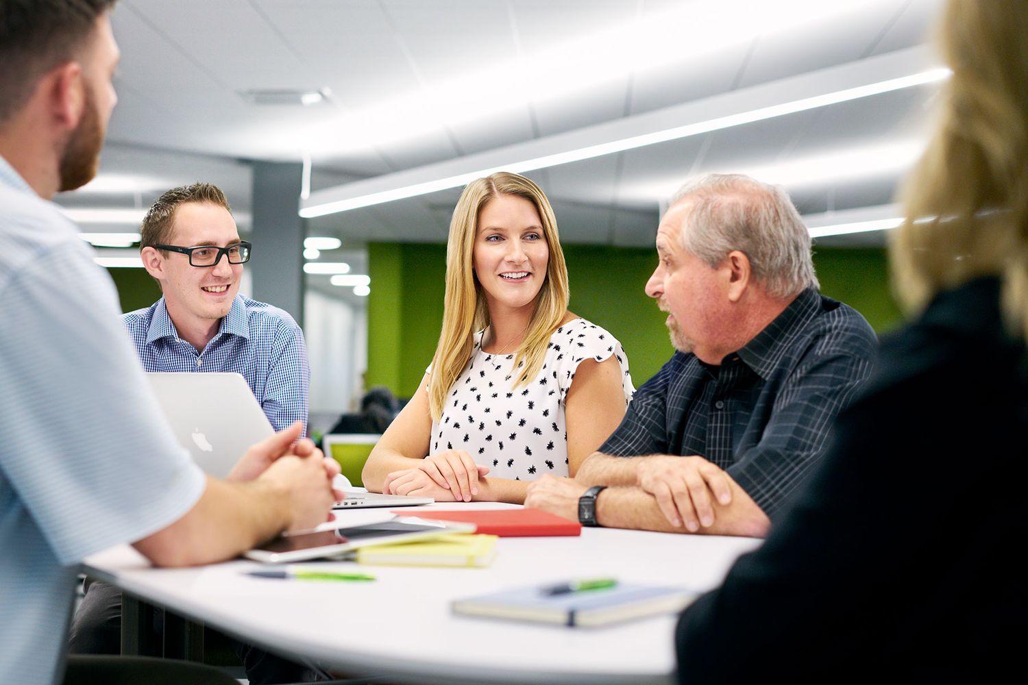 Diverse group of colleagues smiling and collaborating around a table in a modern office.