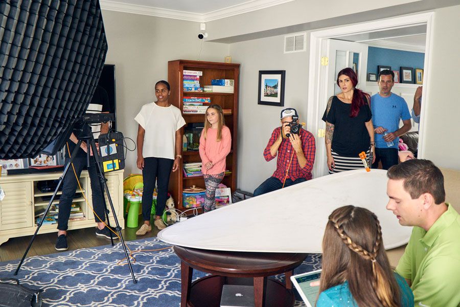 Group of people gathered in a room during a professional photo or video shoot with lighting equipment.