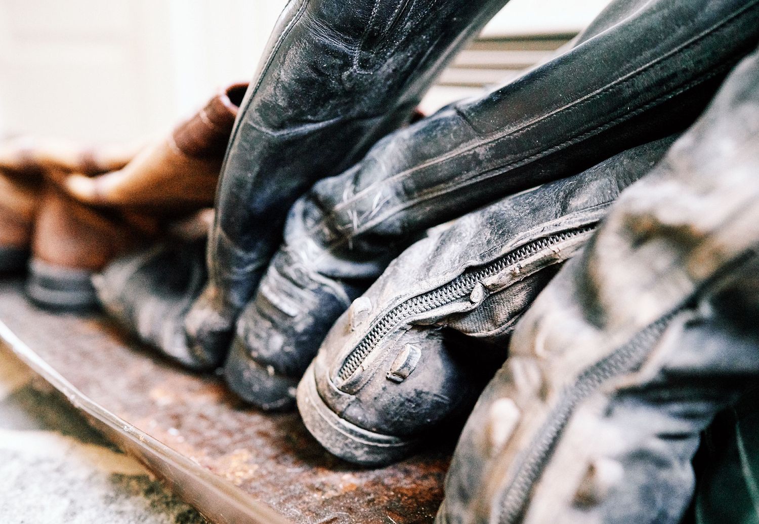 Close-up of muddy worn leather riding boots lined up on a boot tray.