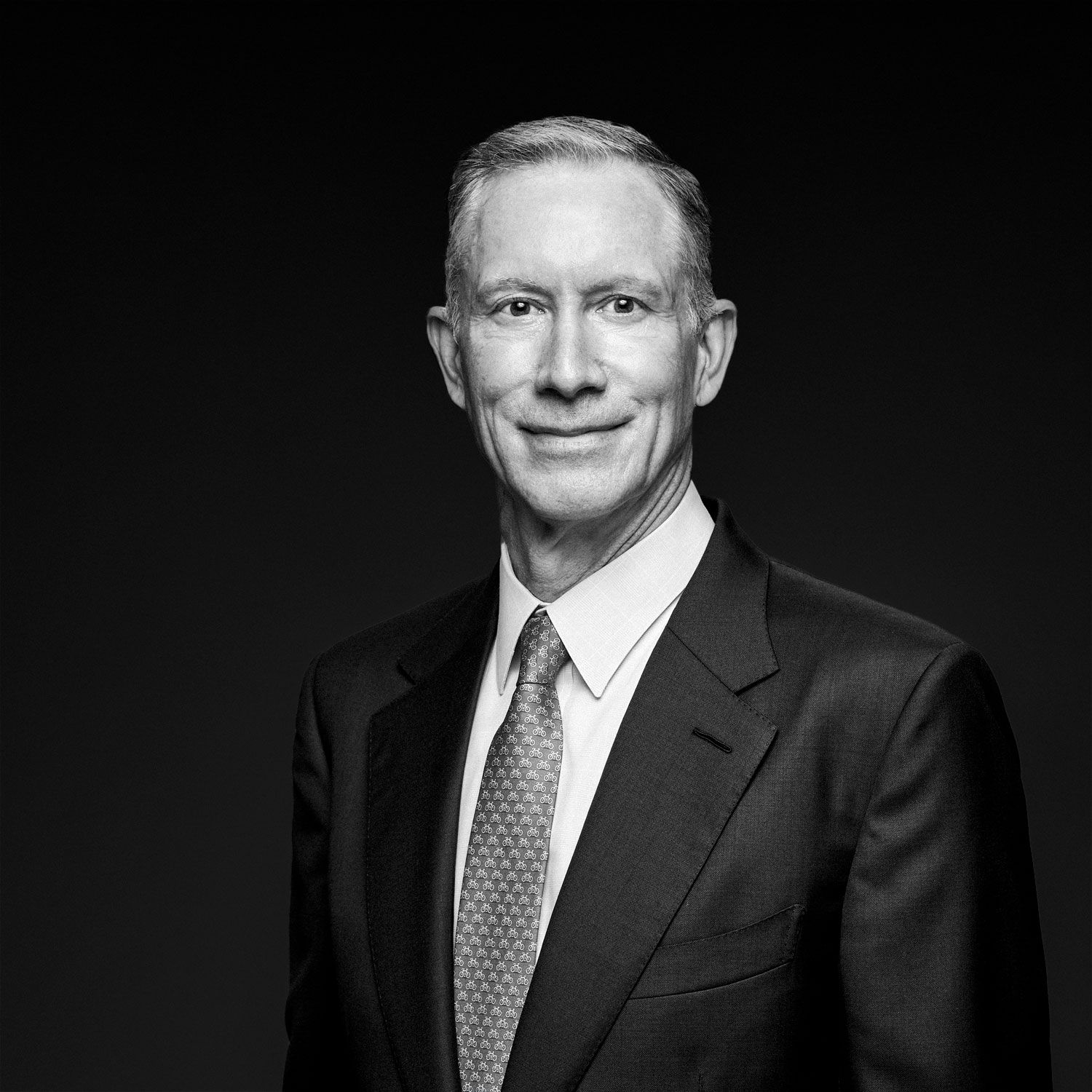 Professional black and white portrait of a senior businessman in a dark suit and tie.