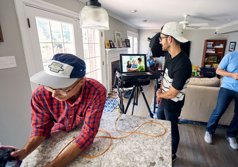 Film crew shooting a video inside a modern home kitchen with camera equipment and monitors.