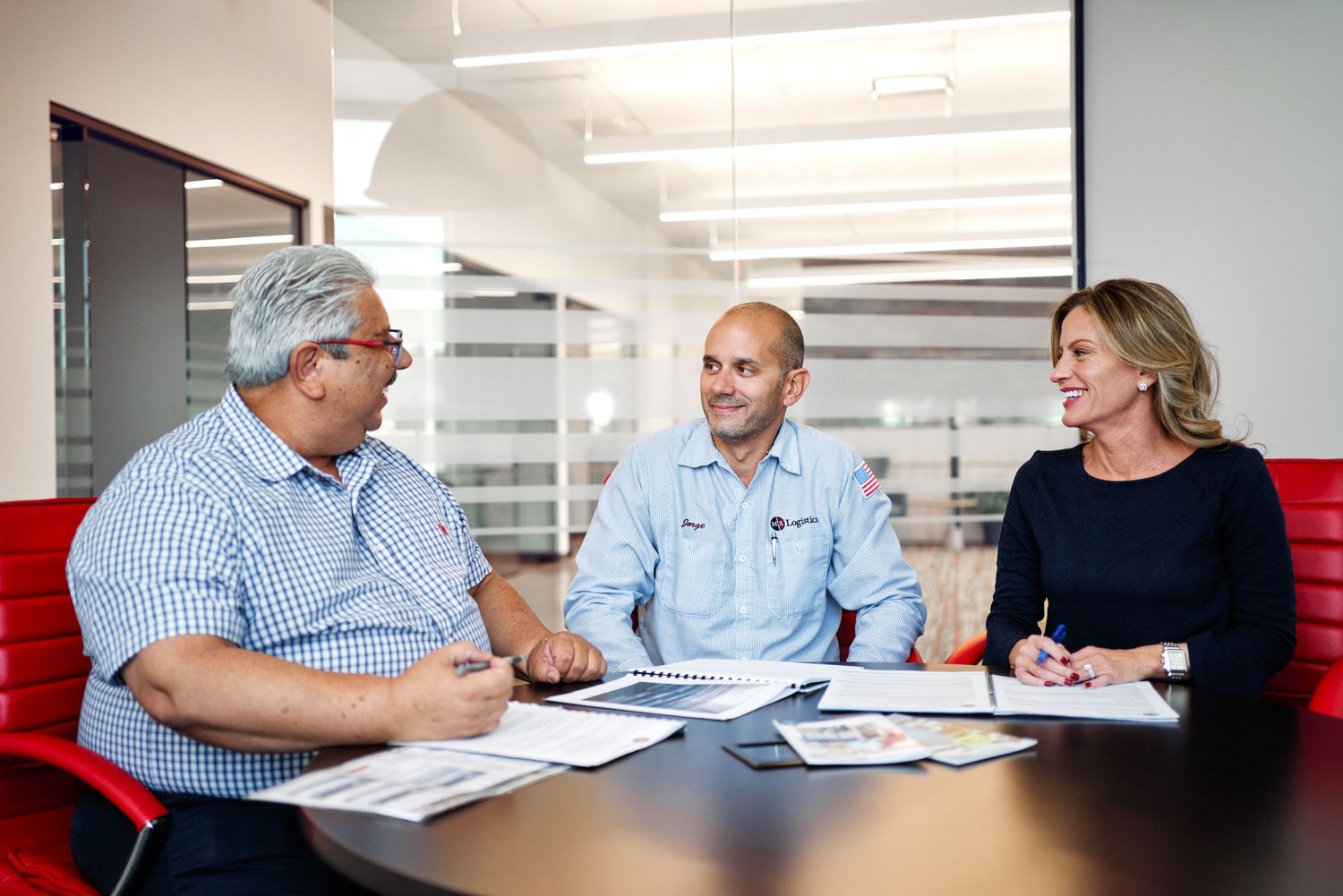 Three colleagues collaborating over documents at a modern office conference table.