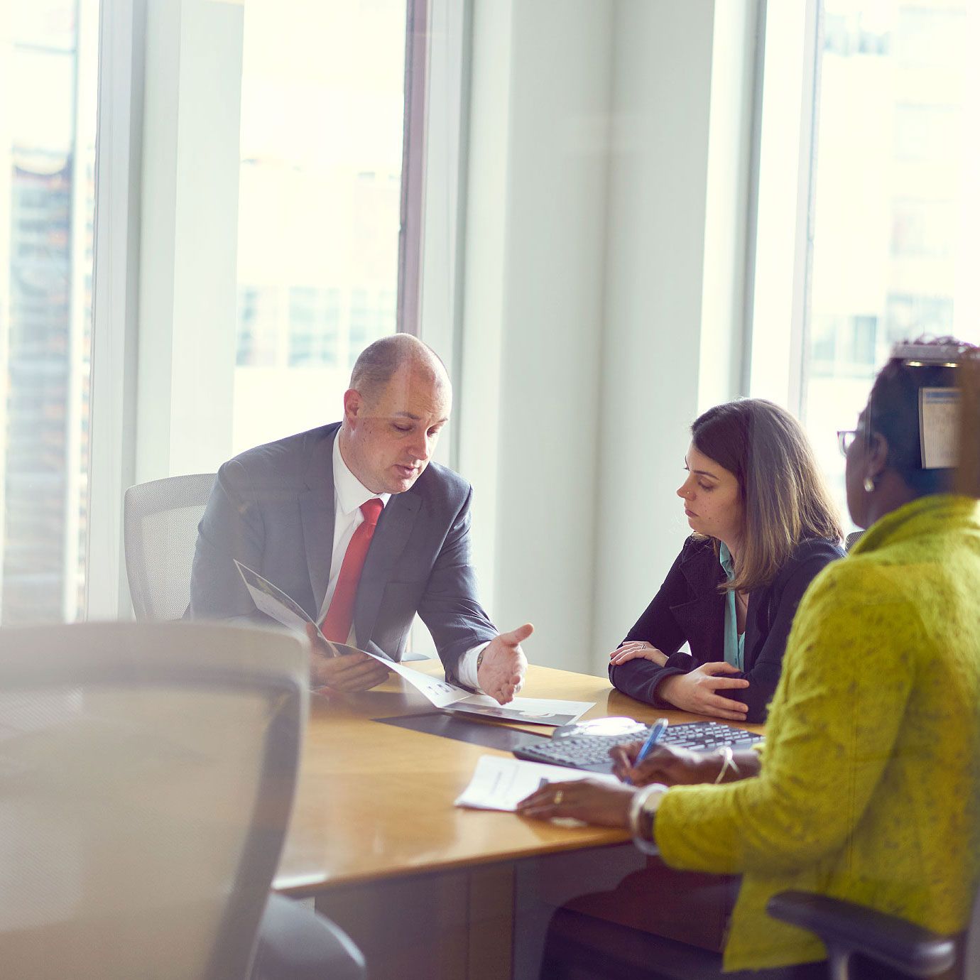 Business professionals having a meeting at a conference table in a modern office with large windows.