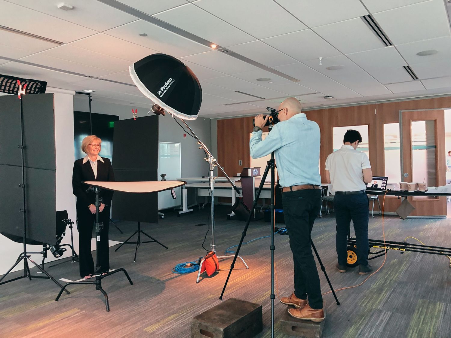 Professional photography studio setup with lighting equipment, photographer, and subject during a corporate headshot session.