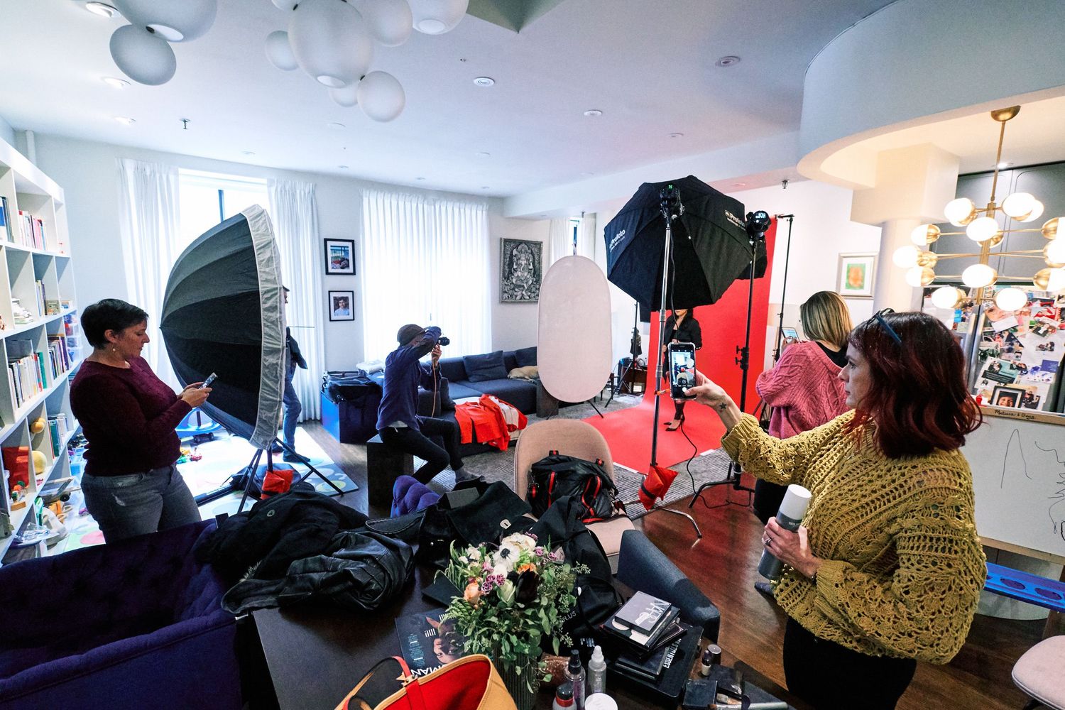 Photography crew setting up professional studio lighting equipment in a modern living room for an indoor photo shoot.