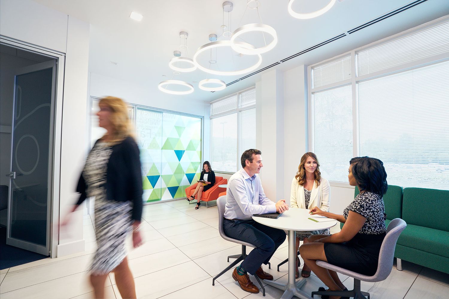 Diverse professionals networking and collaborating in a bright modern office lounge area.