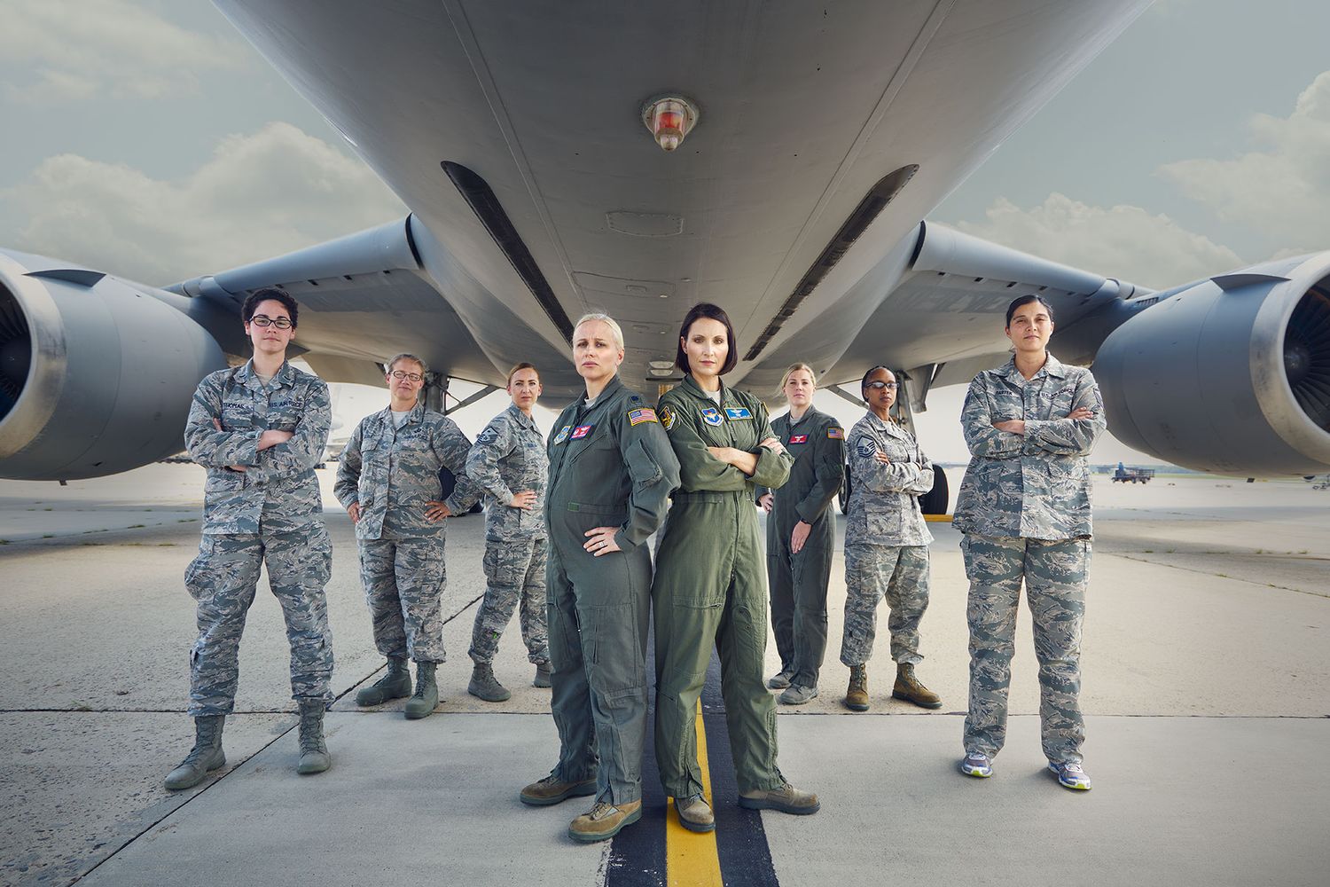 Group of military personnel in uniform standing confidently in front of large aircraft.