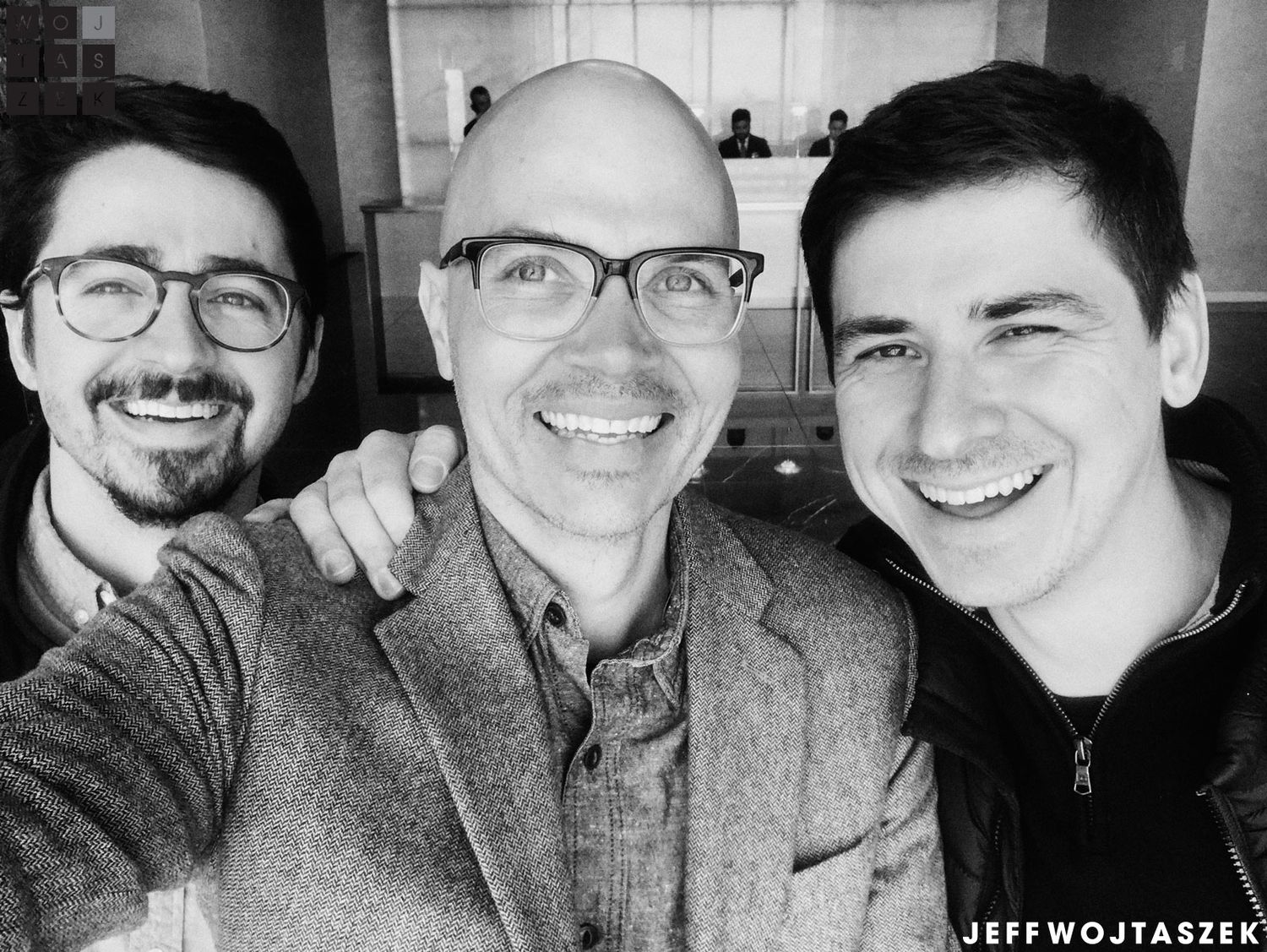 Three smiling men pose together for a selfie in a black and white photo, credited to Jeff Wojtaszek.