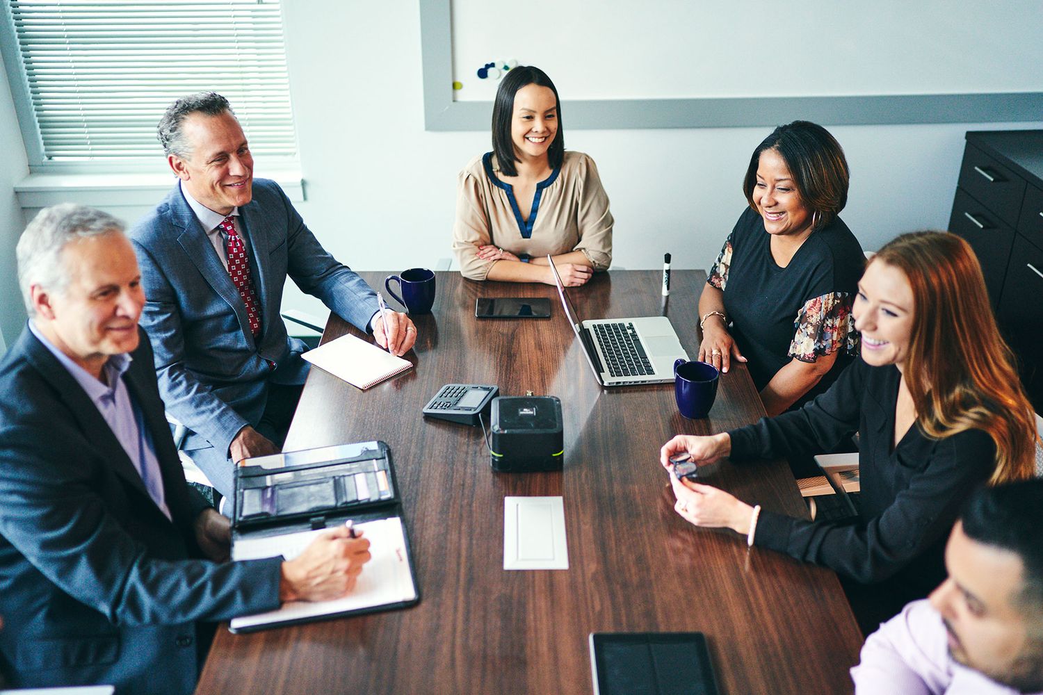 Diverse business professionals having a productive meeting around a conference table with laptops in a modern office.
