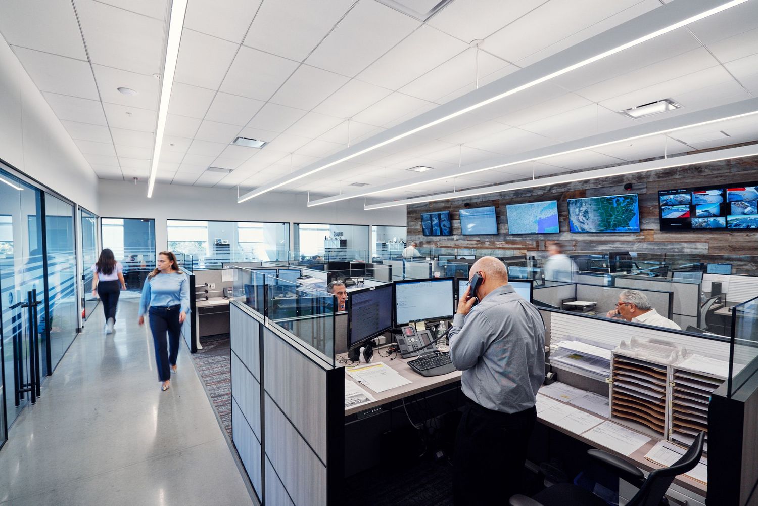 Busy logistics operations center with employees working at computer workstations and monitors.