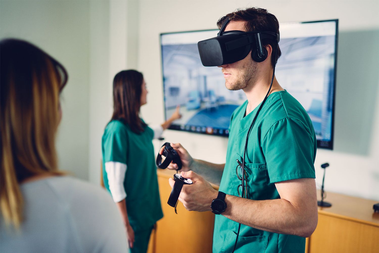 Medical professional in green scrubs using VR headset and controllers in a modern healthcare facility.