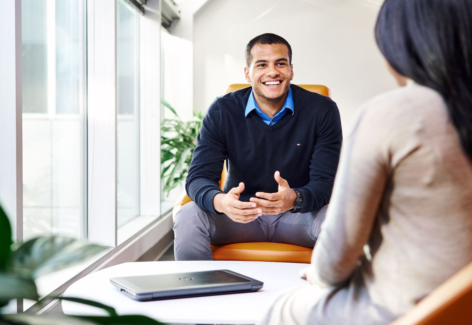 Two young professionals having a friendly conversation in a bright modern office setting.