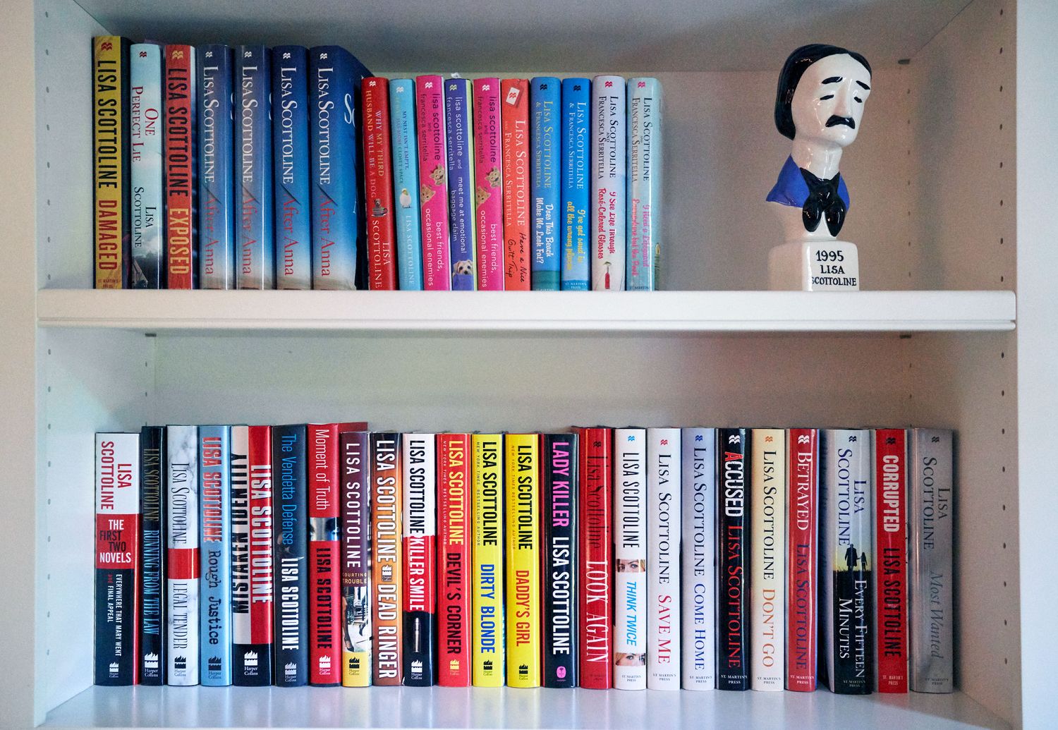 Two shelves of colorful books with an Agatha Christie bobblehead figurine on display.