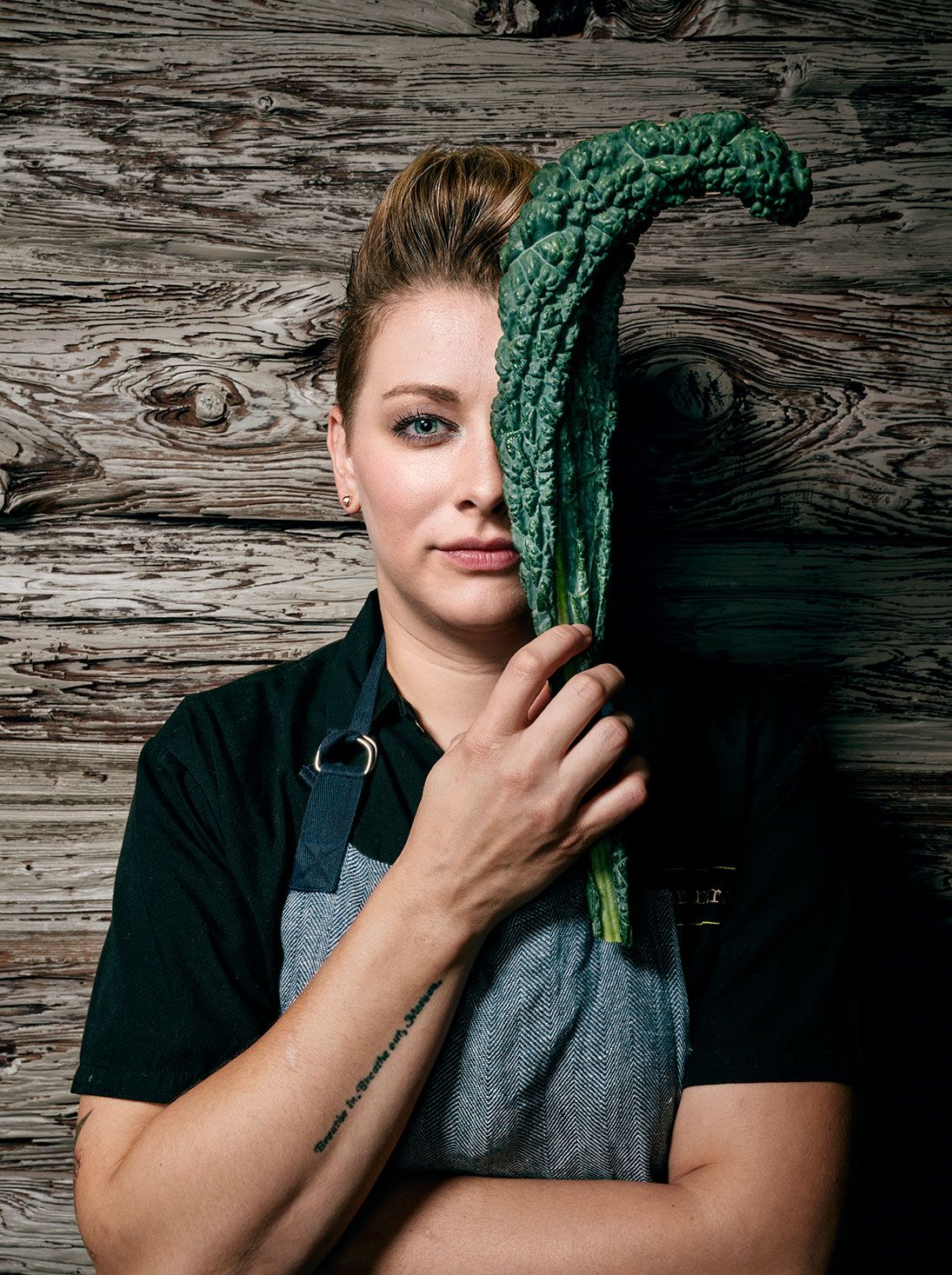 Chef holding fresh kale against rustic wooden background.