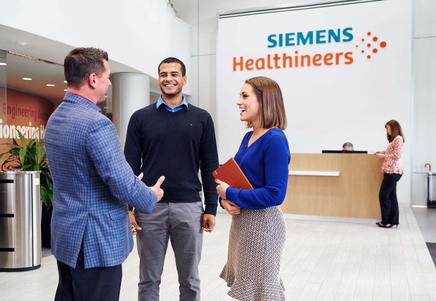 Three professionals greeting each other in the Siemens Healthineers office lobby.