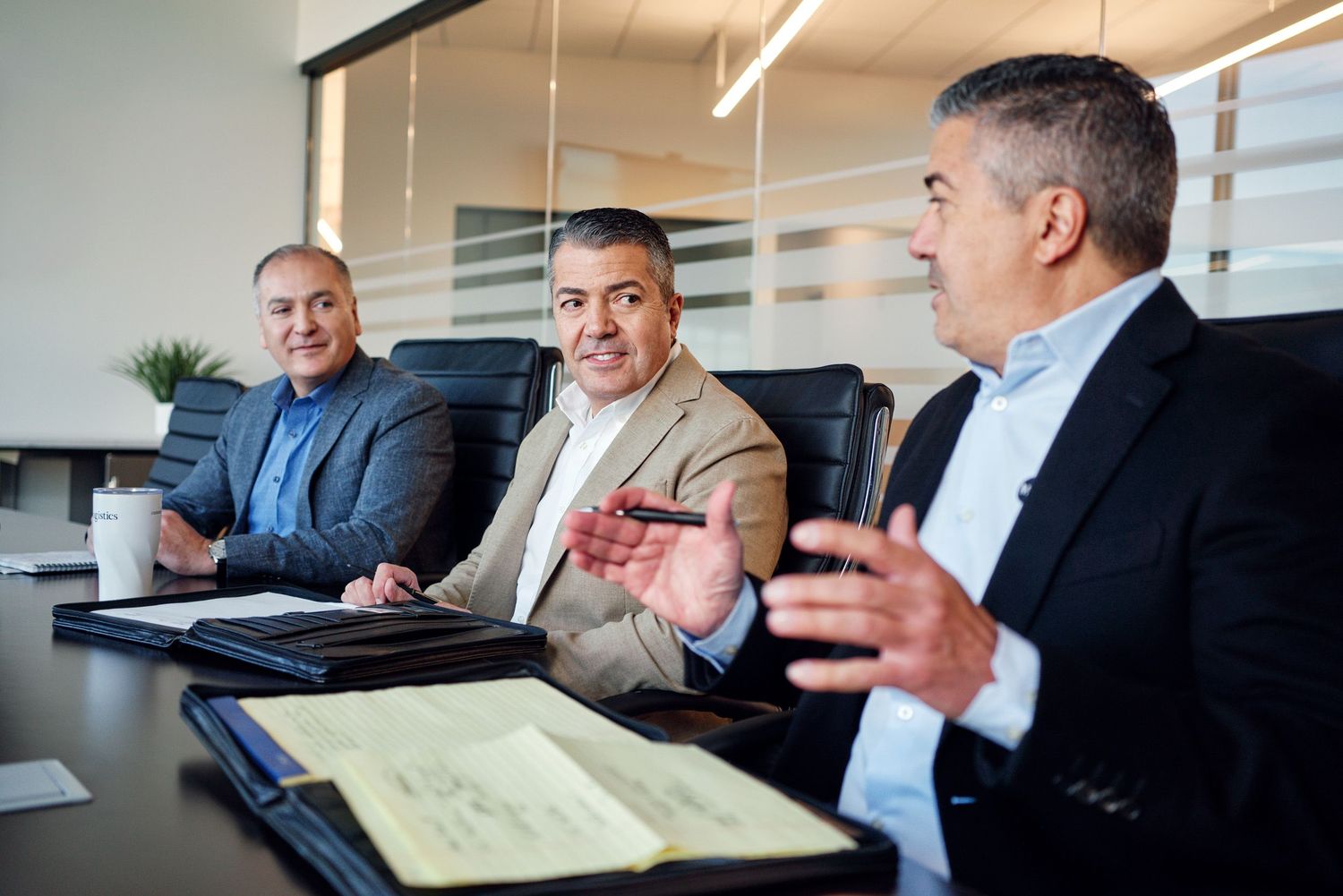 Three business professionals engaged in discussion during a corporate boardroom meeting.
