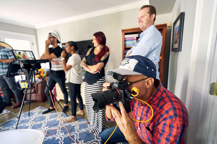 Behind-the-scenes photo shoot with crew members and photographer using professional camera equipment.