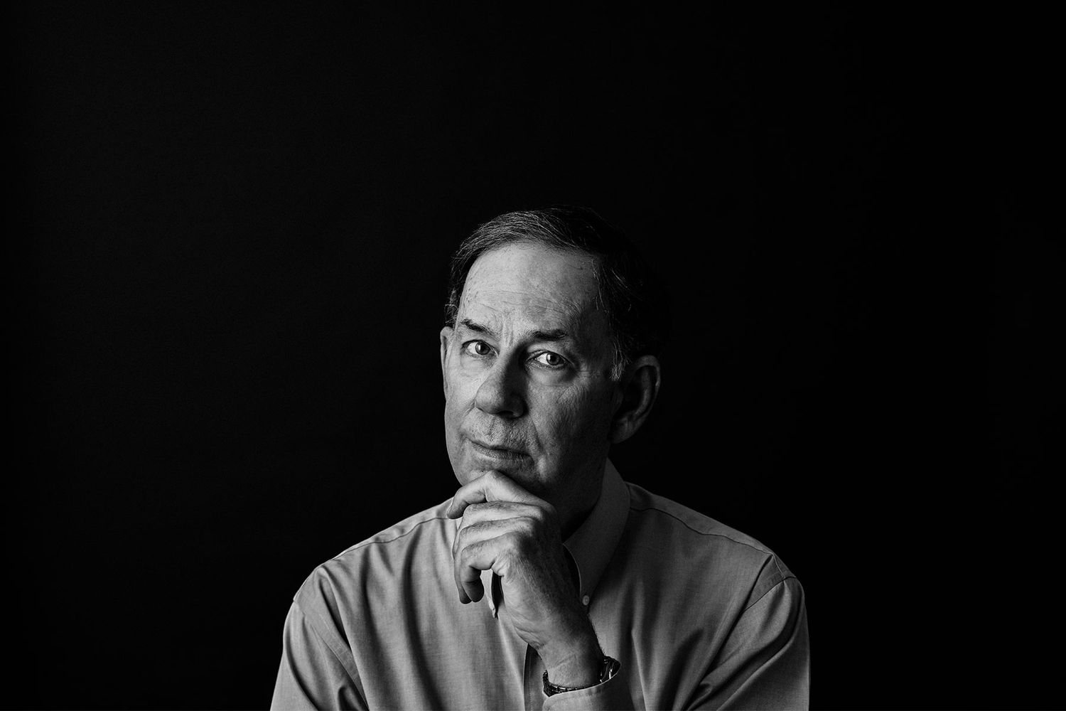 Thoughtful middle-aged man in black and white portrait against dark background.