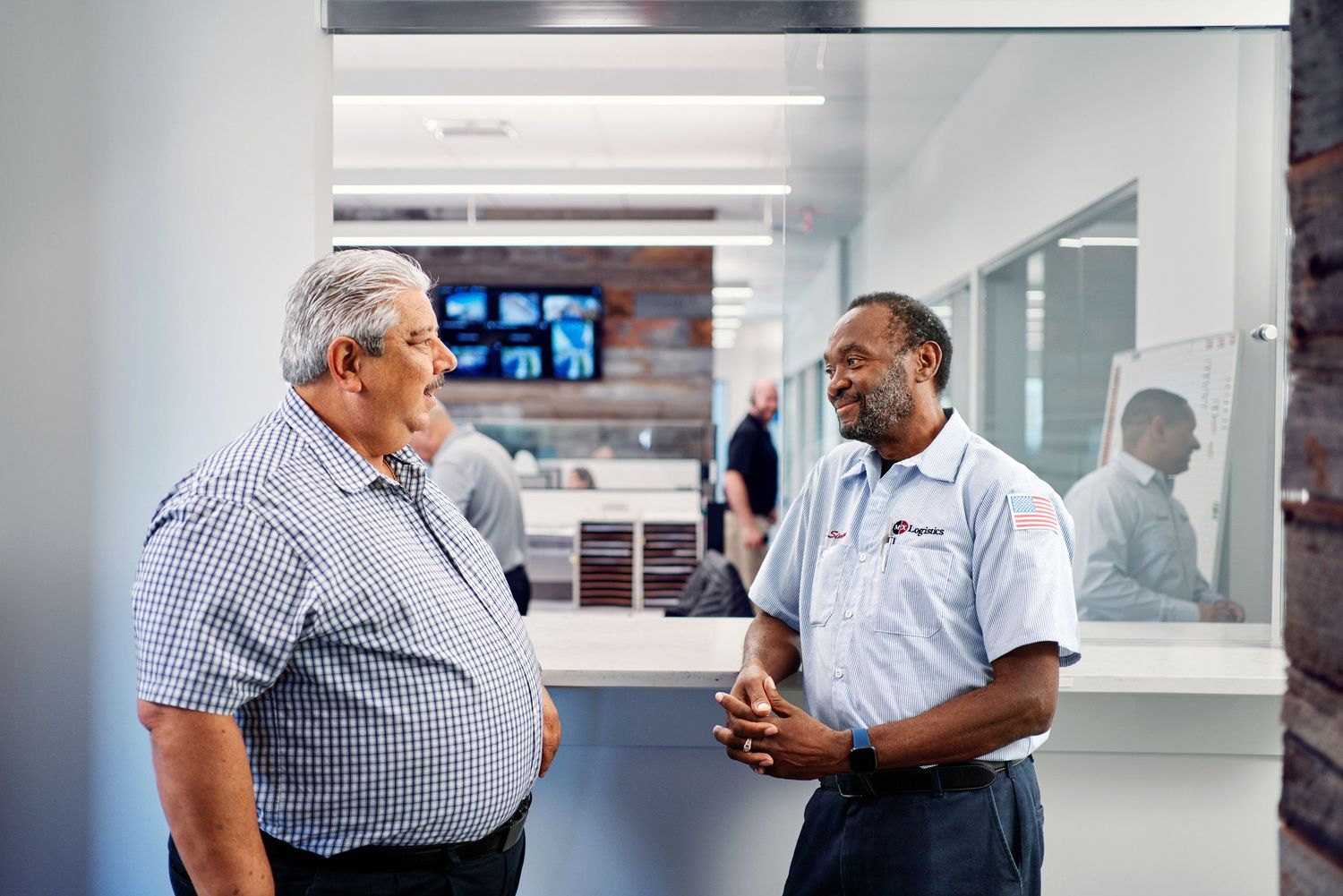 Two logistics professionals having a conversation in a modern office facility.