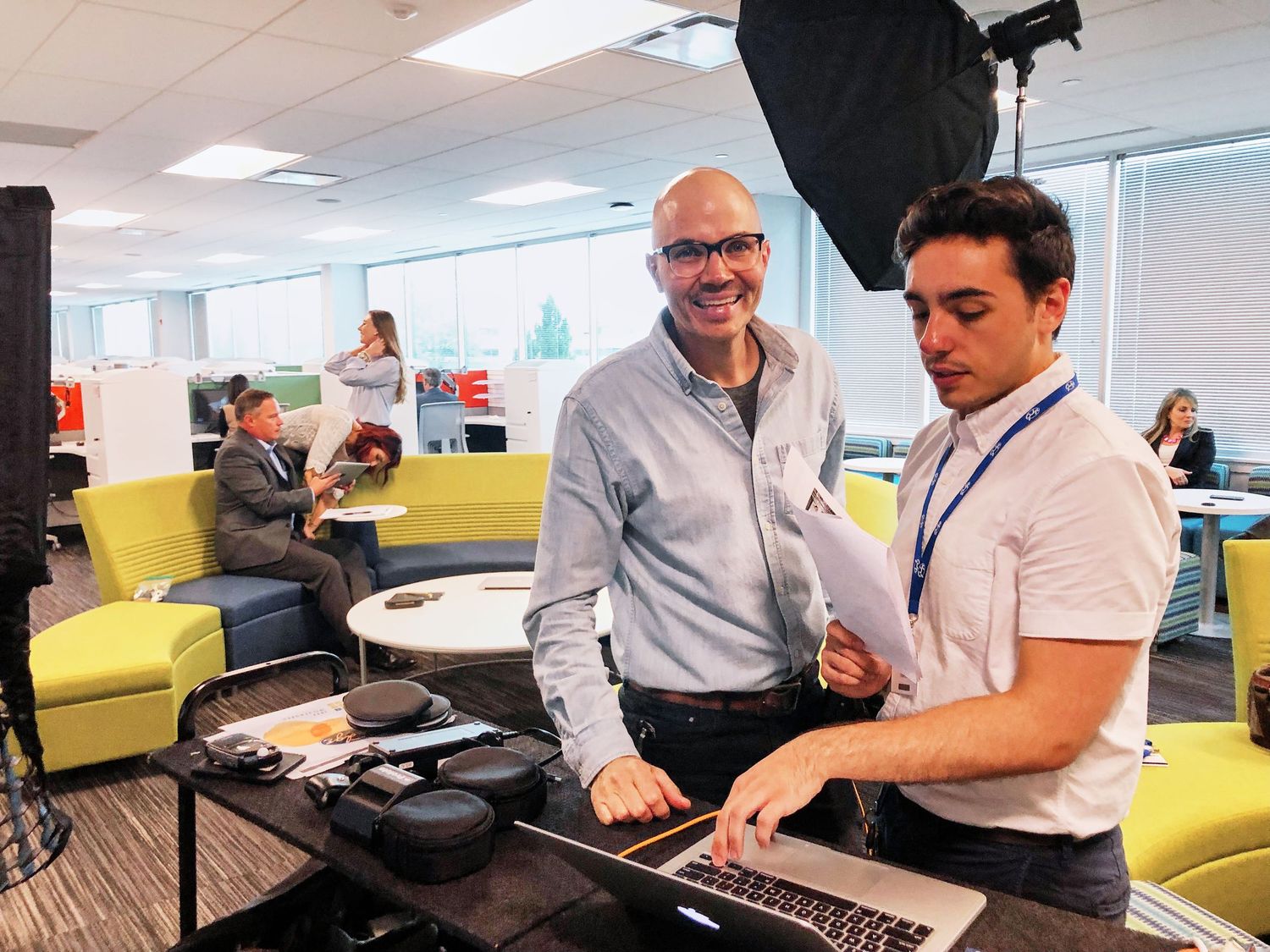 Two men reviewing photos on a laptop during a corporate office photography session.