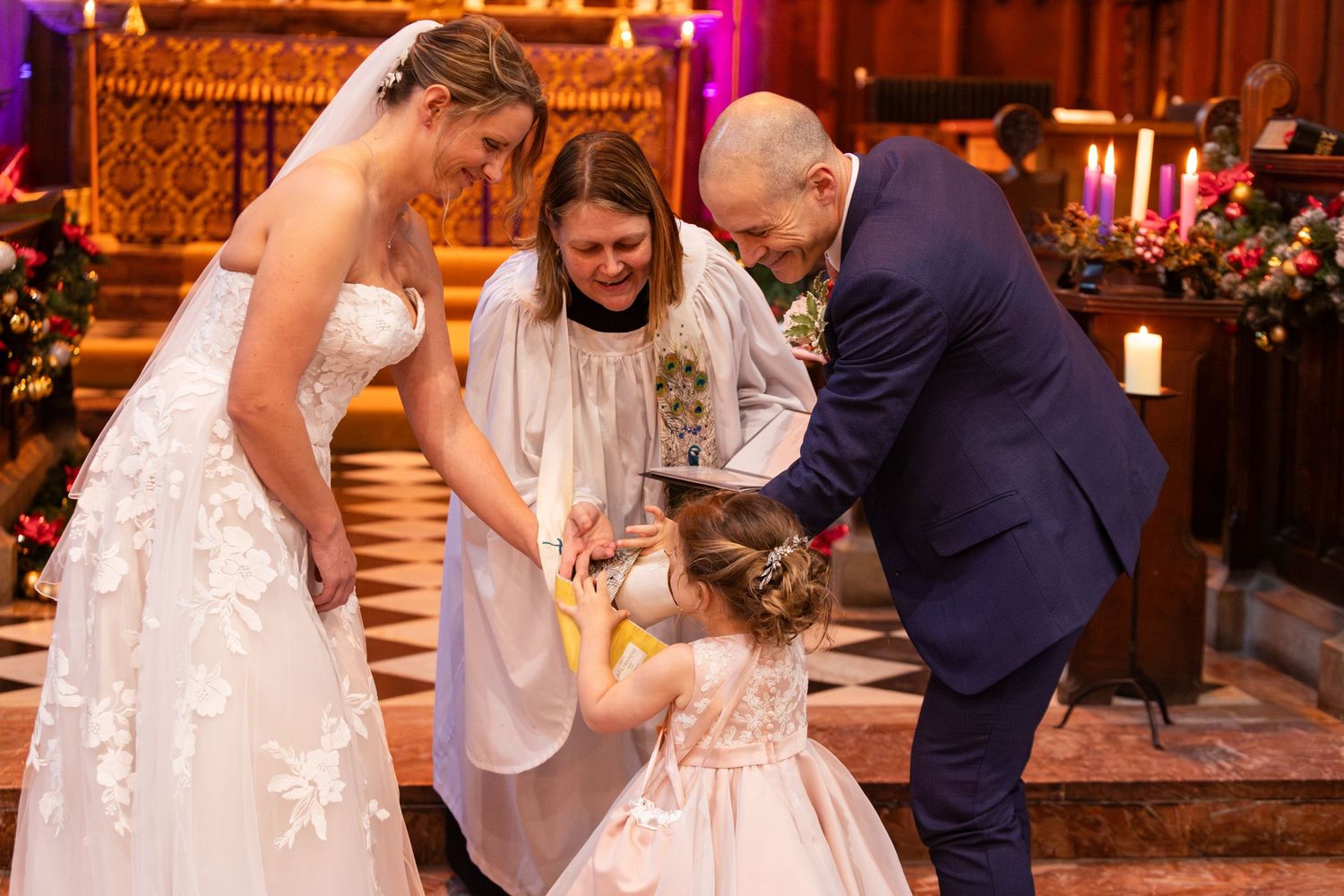 Bride and groom exchange rings with flower girl at an elegant church wedding ceremony.