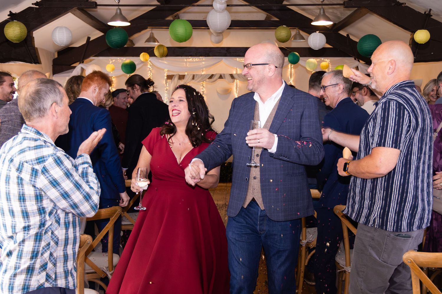Bride in red gown dancing with groom at wedding reception celebration.