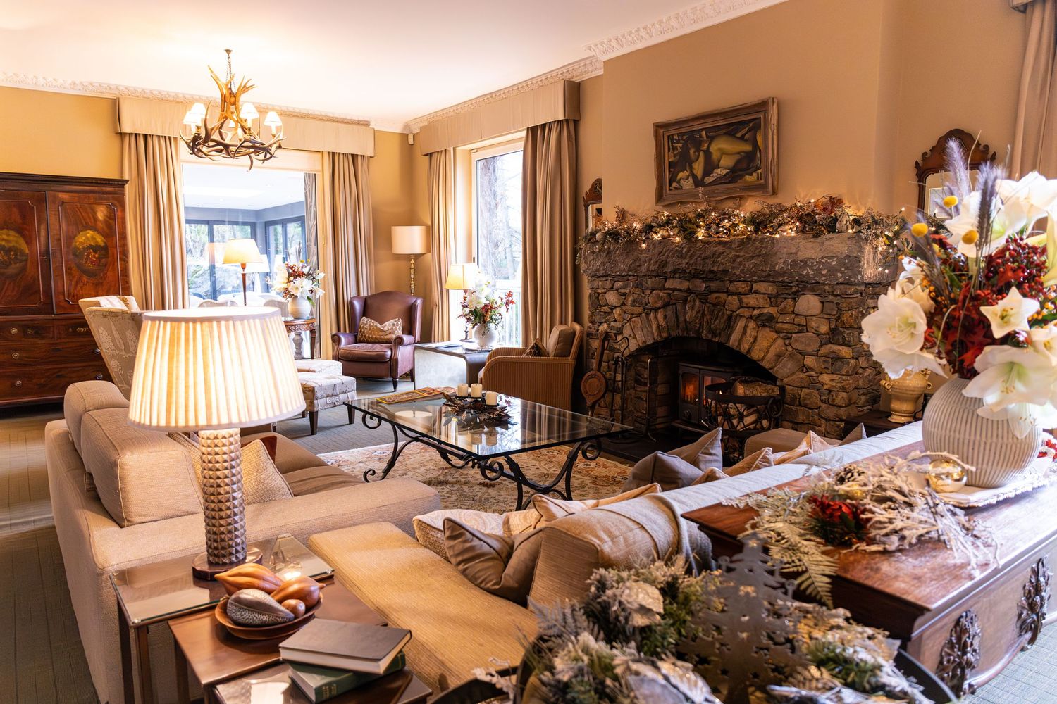 Elegant living room with stone fireplace, plush sofas, chandelier, and warm neutral tones creating a cozy traditional ambiance.