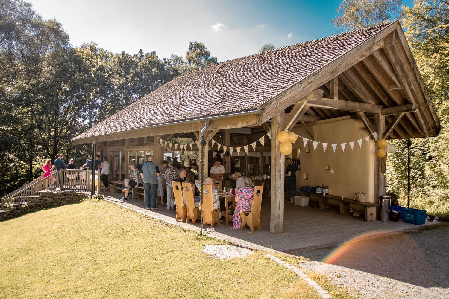 Rustic outdoor wedding venue with timber open-sided barn decorated with bunting surrounded by woodland trees.