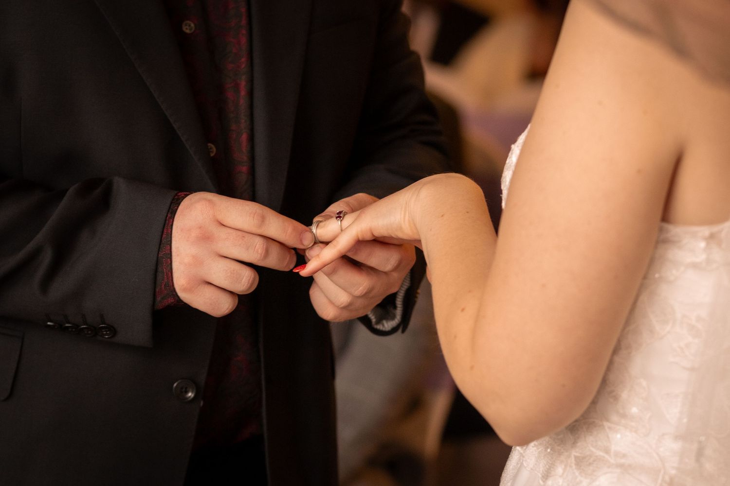 Groom placing a wedding ring on brides finger during a wedding ceremony, close-up shot.