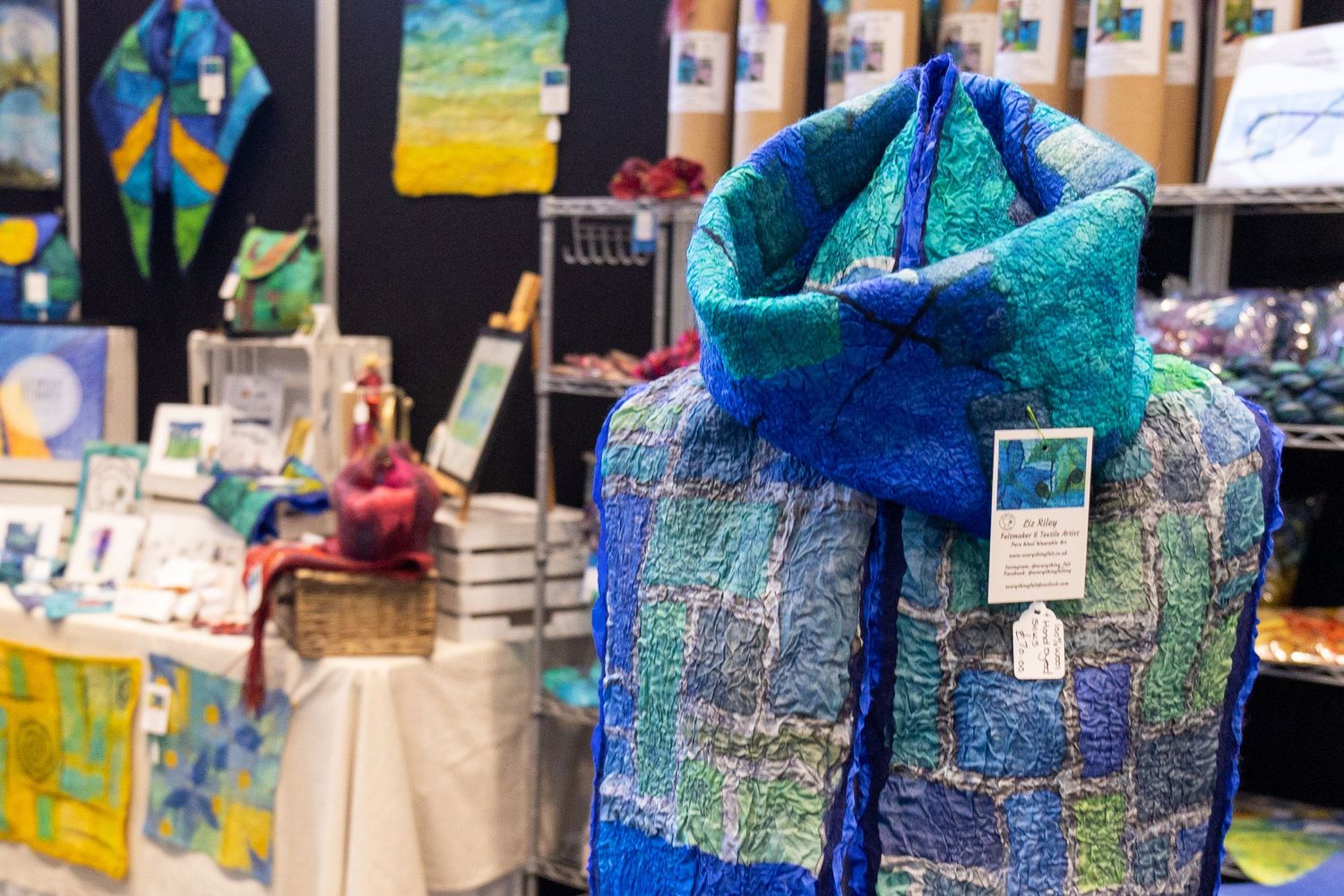 Handcrafted blue and teal felted wool scarf displayed at an artisan craft market stall.