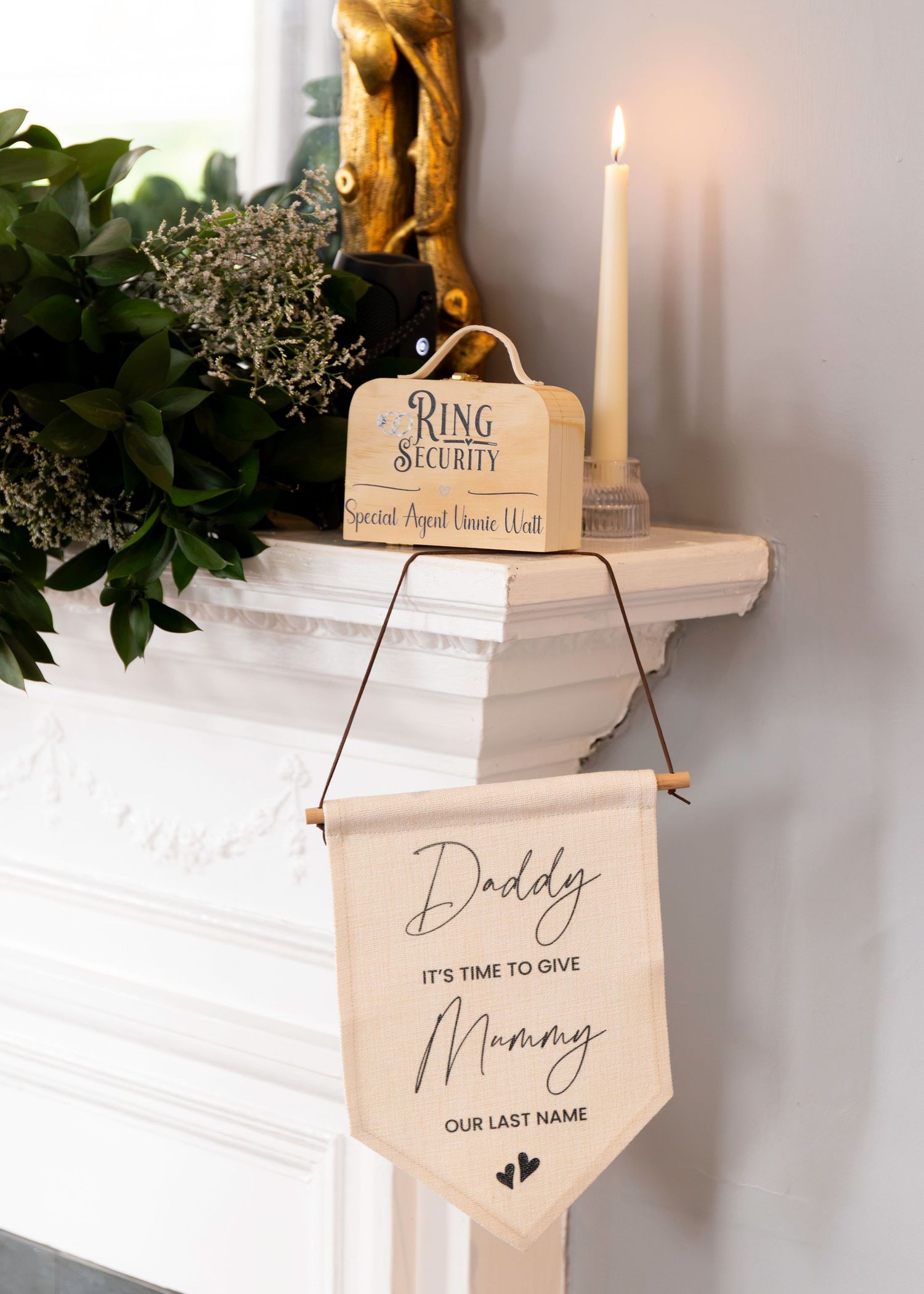 Wedding pennant banner reading Daddy It's Time to Give Mummy Our Last Name, displayed on a mantelpiece with candle.