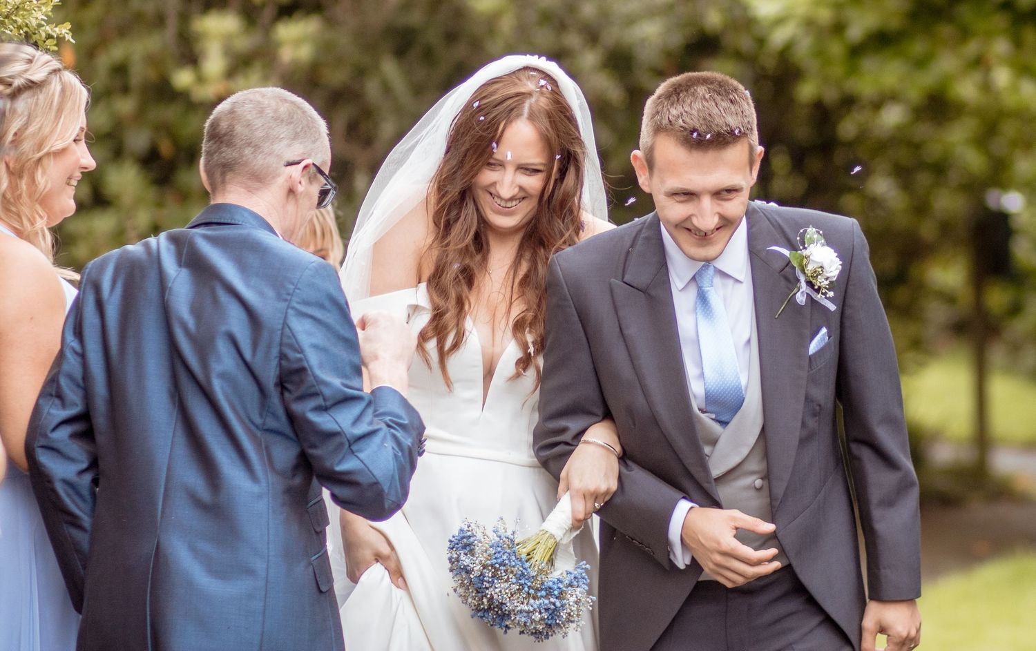 Bride and groom laugh joyfully while walking outdoors after their garden wedding ceremony.